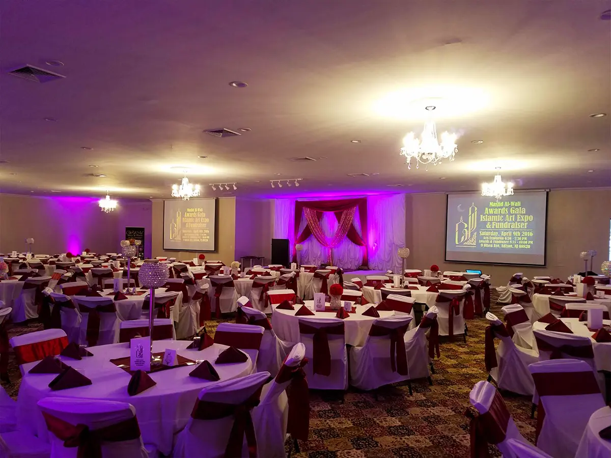 Elegant banquet hall with green decor and floral stage for events and celebrations.