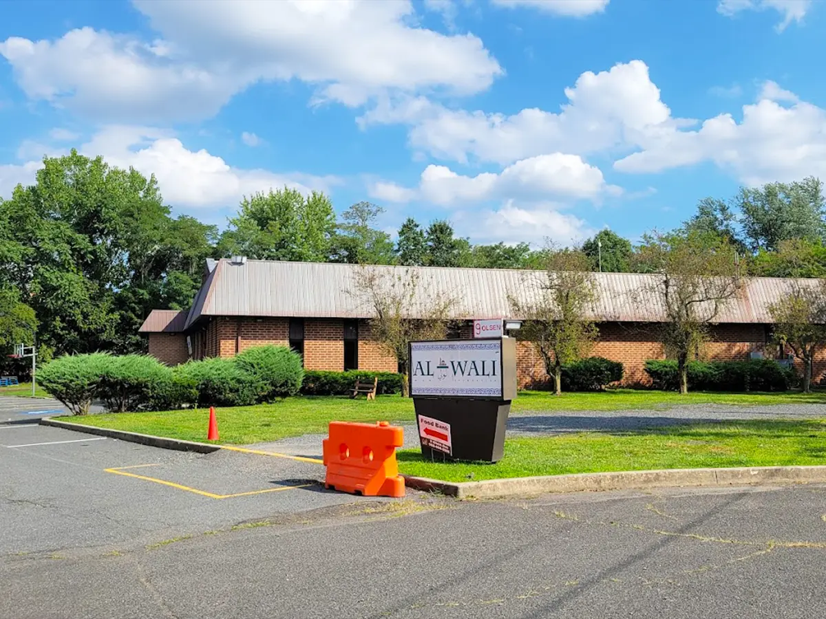 Exterior of Al-Wali community center building with clear signage and lush greenery.