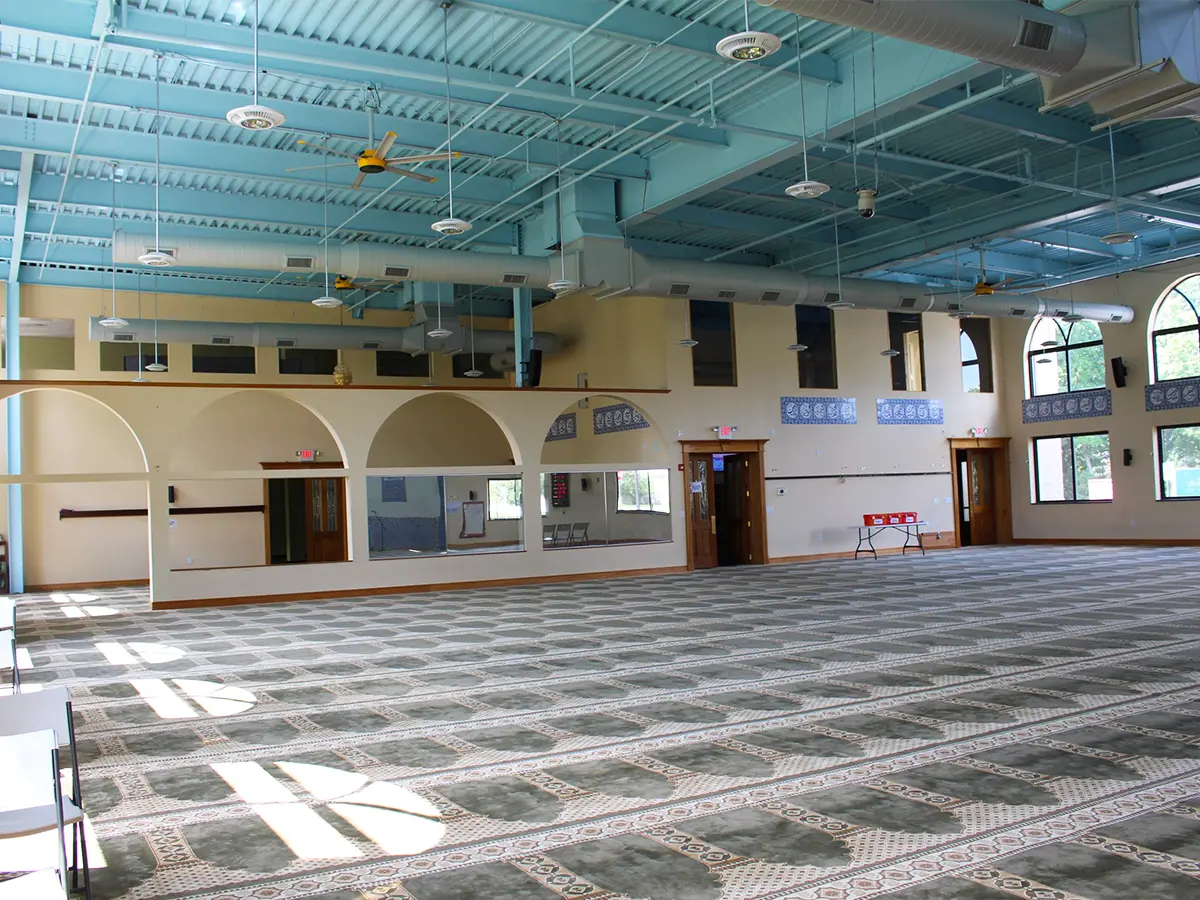 Spacious mosque hall with arched walls and decorative blue-painted ceiling at Al-Wali Center.