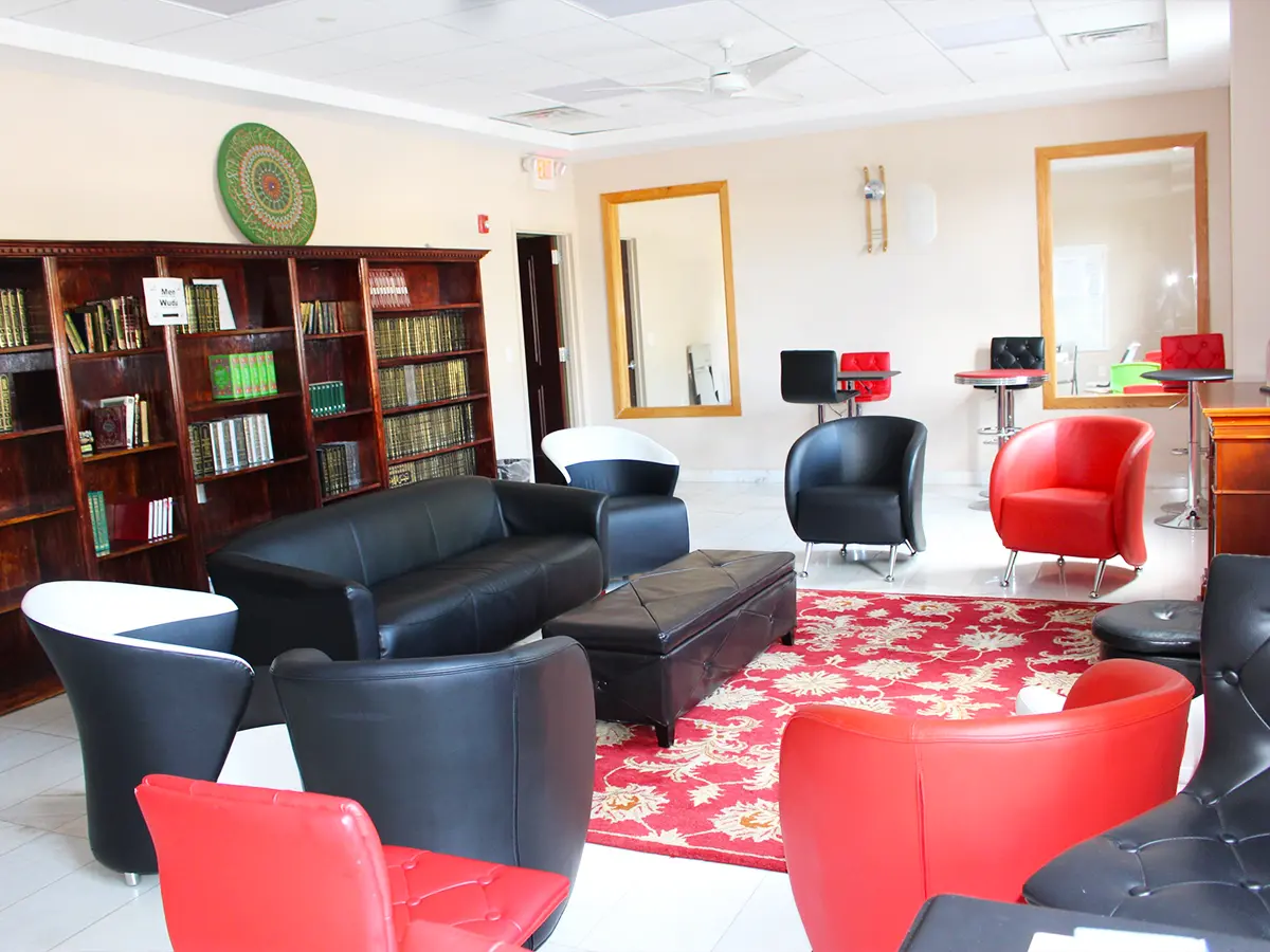 Library lounge with modern black and red chairs and Islamic bookshelf decor in Al-Wali Center lounge.