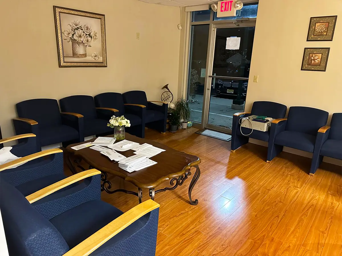 Welcoming healthcare waiting area featuring navy chairs, floral decor, and a coffee table.