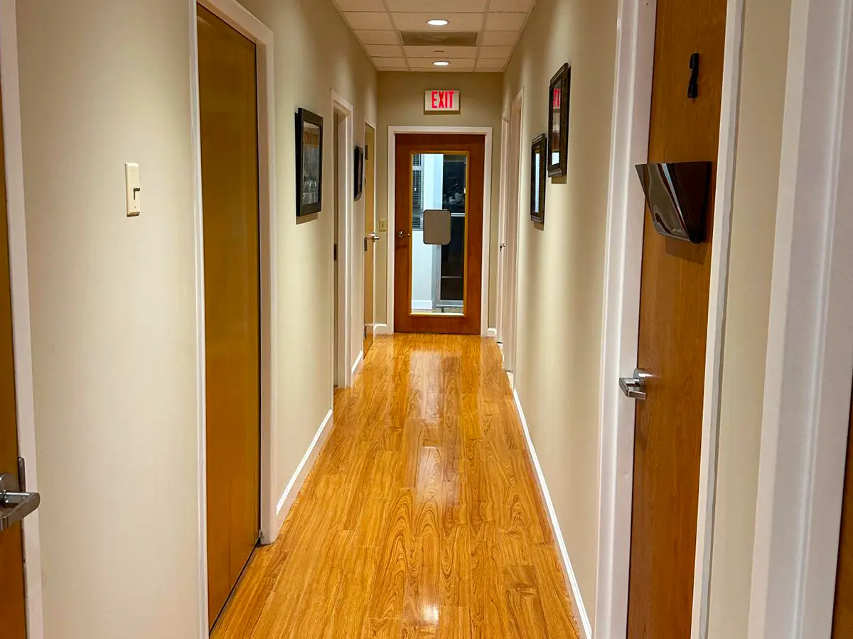 Clean and well-lit hallway leading to patient exam rooms in a healthcare clinic.
