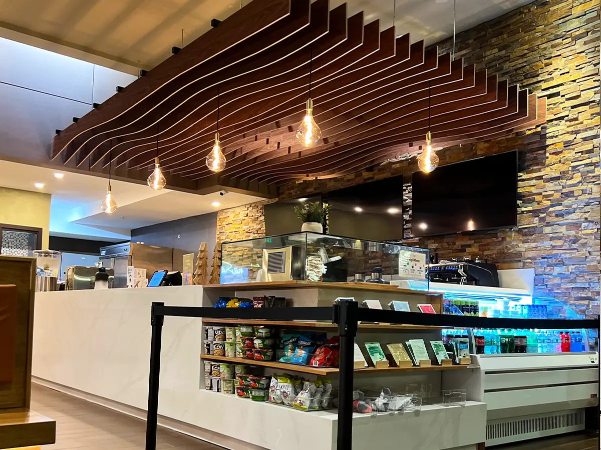 Contemporary juice bar featuring stylish ceiling accents, warm lighting, and a fully stocked snack display.