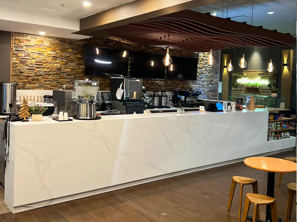 Modern juice bar counter with sleek marble design, stone wall accents, and pendant lighting for a cozy ambiance.