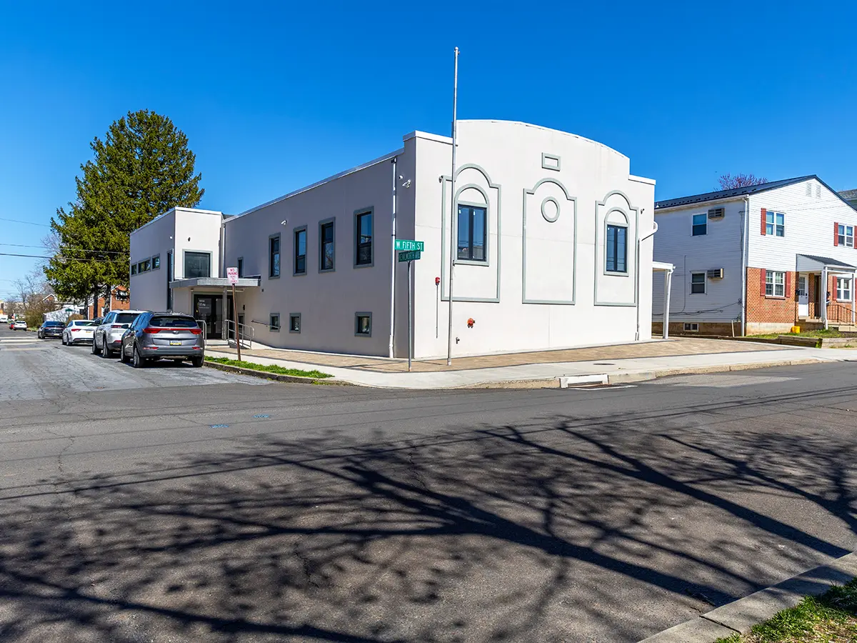 Exterior of a white, single-story community center on a sunny day