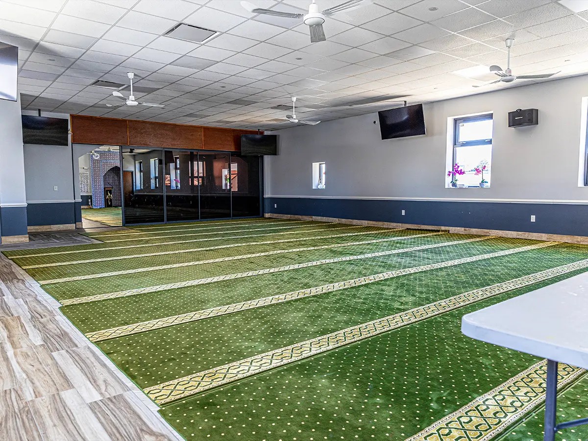 Prayer space with green carpet and glass partitions