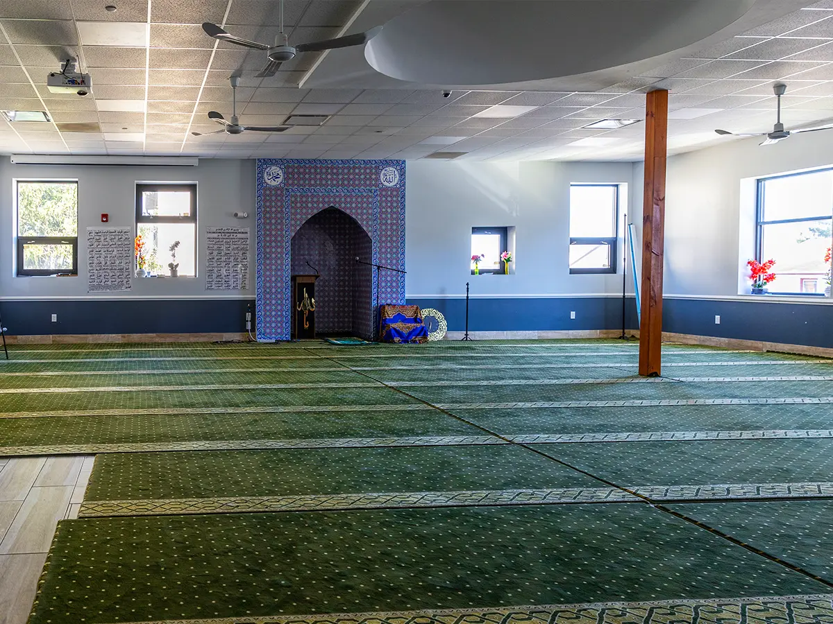 Prayer hall interior with green patterned carpet and natural light