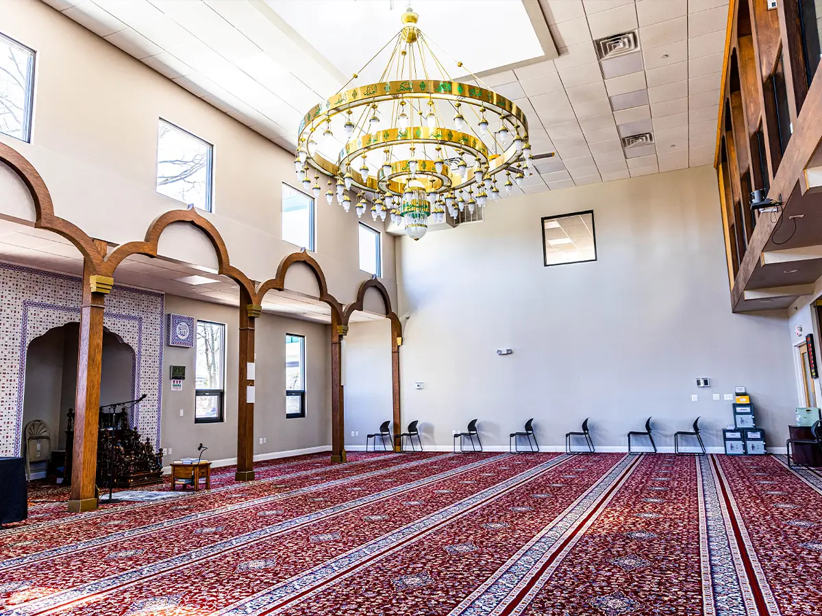 Main prayer hall with a grand chandelier and decorative arches, showcasing Islamic architecture.