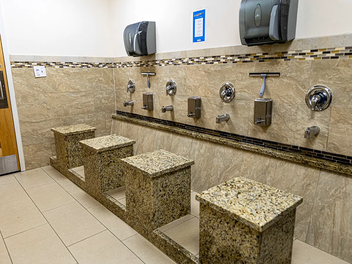 Ablution area with granite seats and modern fixtures in a mosque, designed for convenience and hygiene.